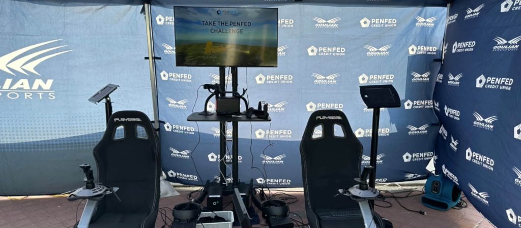 Two flight stations in the branded booth, with a monitor that shows the "Take the PenFed Challenge" attract screen.